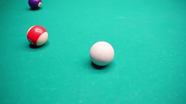 Cue ball and colorful numbered billiards on green felt, shallow depth of field and soft bar lighting, showing a calm setup before the next pool shot.
