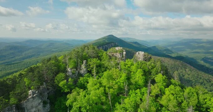 Wide aerial overlook of Chimney Top ridge with layered Appalachian mountains fading into distance, fall yellow greens, symmetry in nature