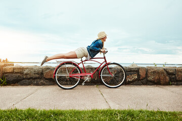 Obraz premium Holiday, outdoor or woman with bicycle stunt, balance development or active hobby for weekend break. Space, fun activity or person with trick execution on sidewalk, skill practice or summer vacation