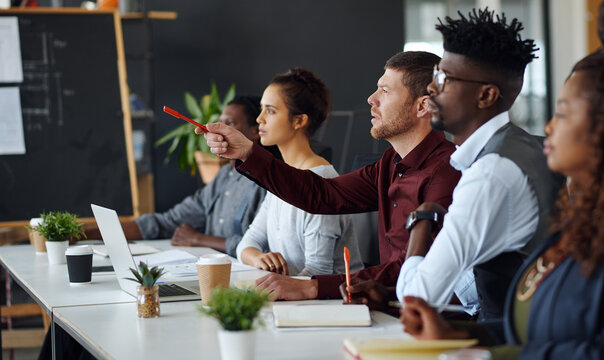 Meeting, pointing or team with feedback in office, creative workshop or idea for planning challenge. Brainstorming, laptop or people speaking for decision making, strategy proposal or suggestion
