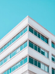 Obraz premium Minimalist white office building exterior with rows of reflective windows against clear blue sky, showcasing contemporary urban architecture
