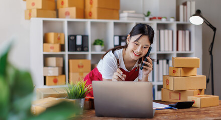Asian woman small businesses SME owners asian female entrepreneurs call phone on receipt box and check online orders to prepare to pack the boxes, sell to customers, SME business ideas online. 