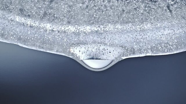 Melting ice block with water drops falling down in slow motion