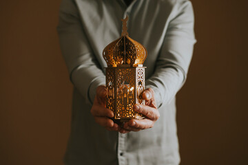 Ornamental Arabic lantern glowing in hand. Festive greeting card for Muslim holy month Ramadan Kareem © erika8213
