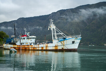 Fishing boat anchored in harbor with mountain backdrop