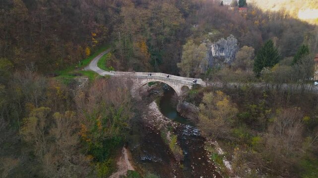 Aerial 4K view of the historic Ottoman Goat's Bridge at dusk, ancient stone arch over Miljacka river canyon, Sarajevo travel, Bosnia and Herzegovina, drone