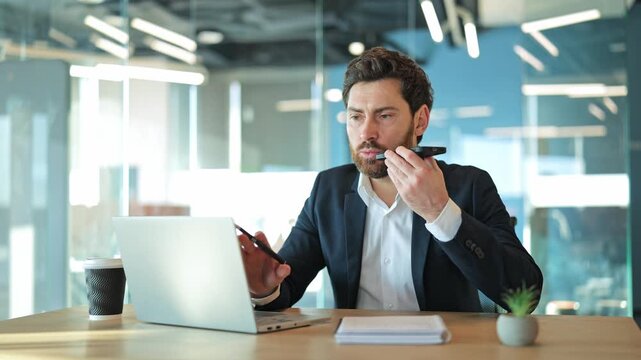 Professional communicates using smartphone records a voice message in a modern office. Determination while dictating important messages, conveying efficiency and seriousness in daily tasks.
