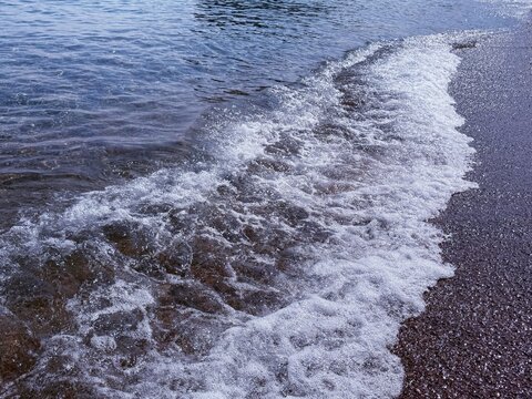 Sea waves foam rolling on the pebble beach.