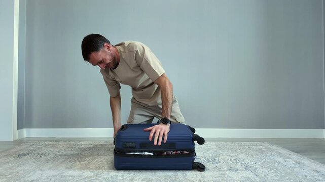 Timelapse of a determined young man forcefully closing an overfilled suitcase before a trip