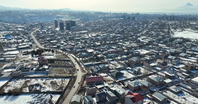 Aerial view A quiet and serene Yerevan Armenia cityscape covered in snow. The streets are lined with houses, and there are a few cars in motion