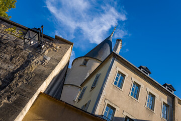 Upward view of a traditional building with a pointed turret and textured stone wall under a vivid blue sky in Nevers, Burgundy. The composition features classic architectural details, soft sunlight © Florent