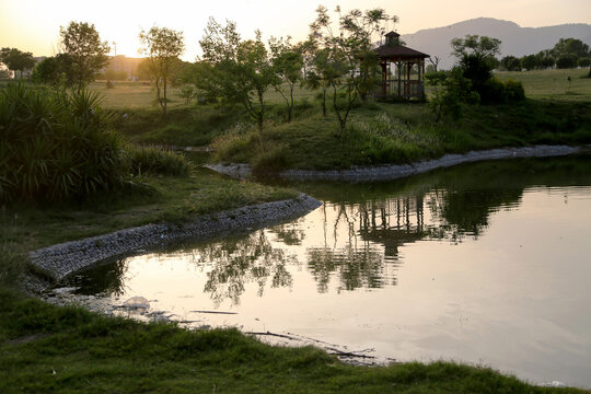 Fatima Jinnah Park F9 Islamabad Pakistan sunset landscape with lake reflection, trees and gazebo, peaceful evening view in urban nature park, scenic capital city environment
