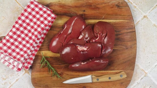 Rognons de porc crus entiers sur planche en bois