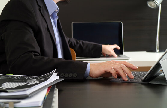 Business Professional Working on Laptop and Tablet at Modern Desk