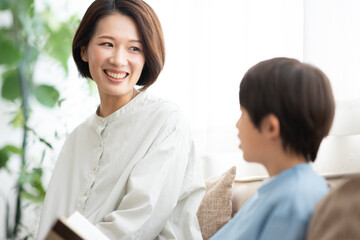 本を読む男の子とソファに座る母親