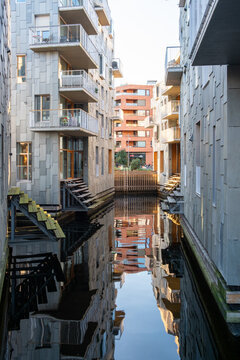Symmetry in an alley canal between apartments shows urban modern architecture in Oslo Norway with reflections through the narrow waterway