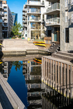 Urban modern architecture and apartments border a canal waterfront in Oslo Norway where steps descend to reflections on still water