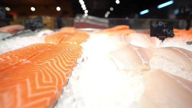 Fresh salmon fillets and other fish displayed on ice in a supermarket seafood section.