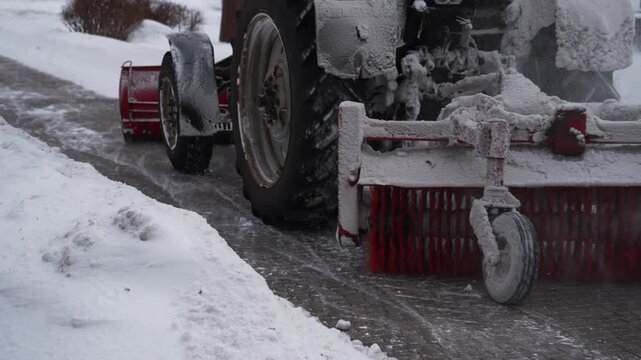 Snow removal car with rotating brush cleans snow the street during a snowfall. Snowplow removing fresh snow from city square