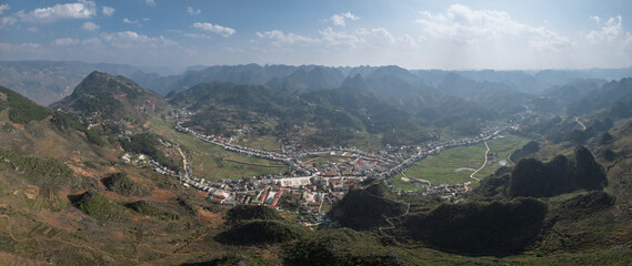Panoramic view of town, winding roads, and distant mountain ranges.