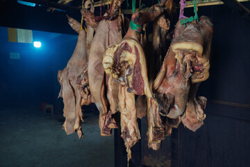 Close-up of raw pork cuts hanging inside a traditional smokehouse.