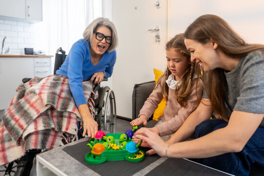Three generations of women playing board game at home
