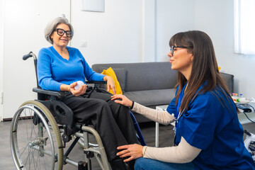 Obraz premium Caregiver talking with senior woman sitting in wheelchair