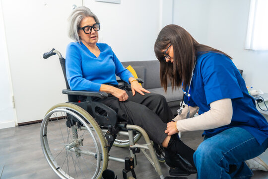 Caretaker assisting senior woman in wheelchair getting dressed