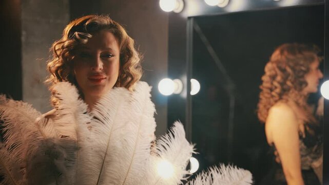 Beauty blonde hair sexy face retro lady looking into camera hand holding waving with fan of natural white ostrich feathers. woman burlesque show actress. Flapper girl 20s roaring twenties old style.