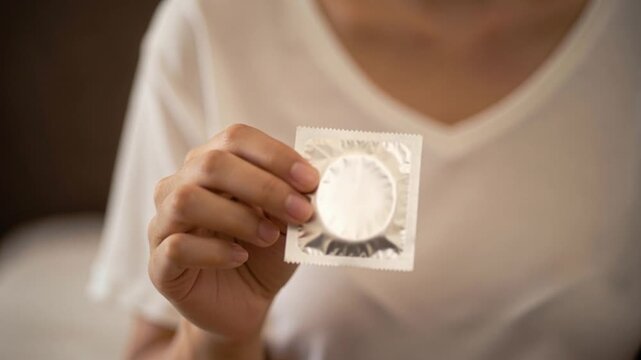 Holding Unopened Condom Pack in Hand Focused on Health and Safety