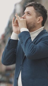 Man with stubble playing harmonica on the street