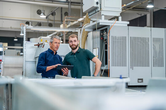 Engineers looking at machines in factory