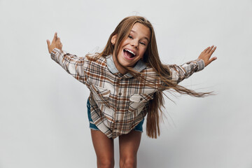 Girl smiling and leaning forward with arms outstretched wearing plaid shirt and shorts against...
