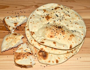 Stacked golden flatbreads with scattered sesame and nigella seeds