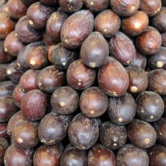 A close-up, textured pile of ripe, dark brown, oval fruits