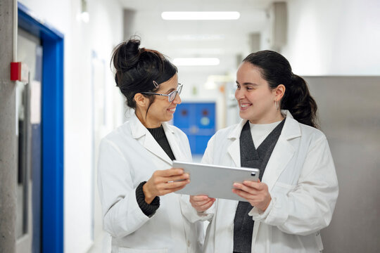 Scientist collaboration with tablet in modern laboratory hallway