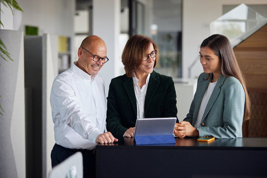 Colleagues standing near table and using tablet PC at office