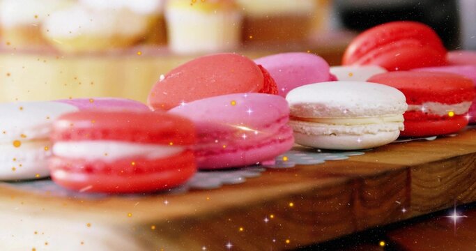 Displaying colorful macarons resting on wooden board in bakery, with paper doily and golden sparkle