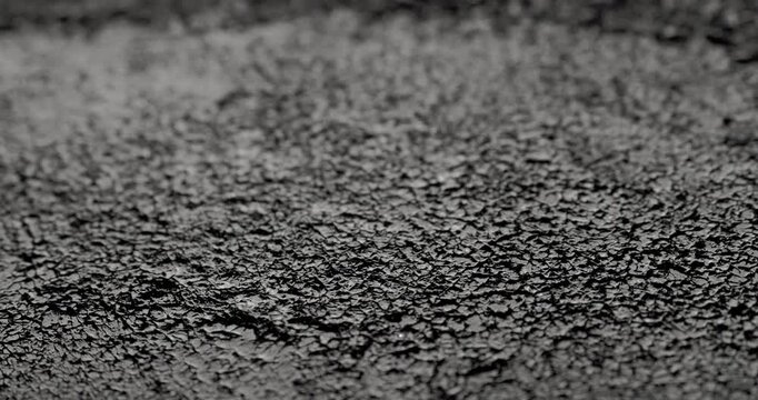 Macro Cracked Mud Texture on Black. Slow panning footage across a fissured dark surface, showcasing intricate polygonal crack patterns and rough granular details under subtle directional lighting.