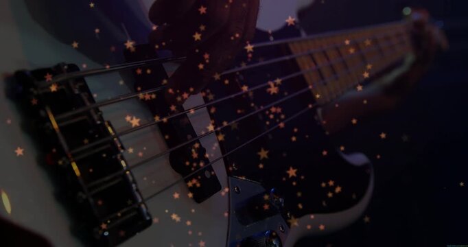 Male bassist plucking pickups starting string motion while fretting, gold stars drifting over music