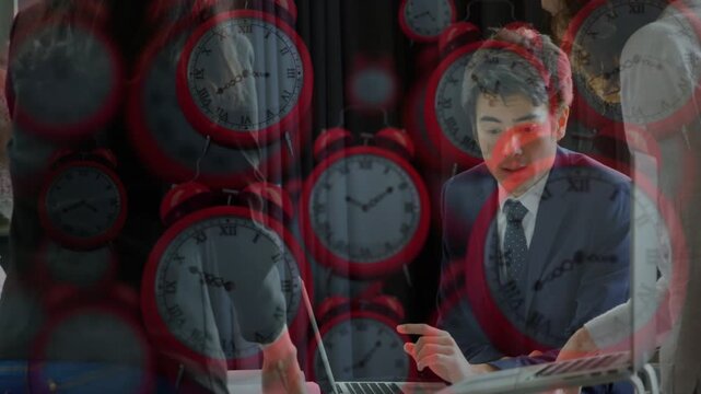 Man at laptop starting gesturing guiding team pointing raising finger in business with red clocks
