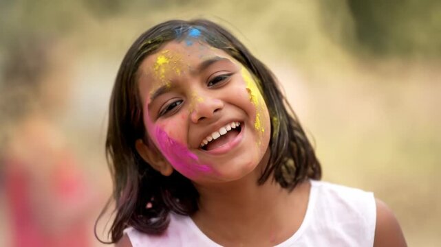 Close-up of Cheerful Indian Girl Smiling During Colorful Holi Festival Celebration.