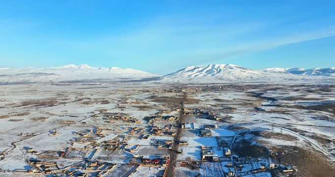 A snowy mountain landscape with a small town in the distance