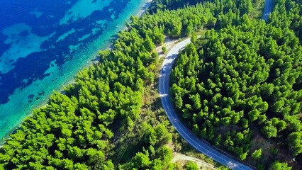 Obraz premium Aerial View of Serpentine Road Cutting Through Lush Forest and Turquoise Waters Below