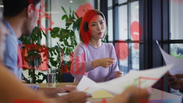 Woman handing papers and speaking, red graphics rising and partly hiding, leading business meeting