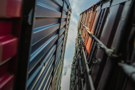 Low angle perspective of cargo containers forming corridor toward sky, abstract industrial composition, logistics network concept, freight transportation, container terminal, modern global commerce ba