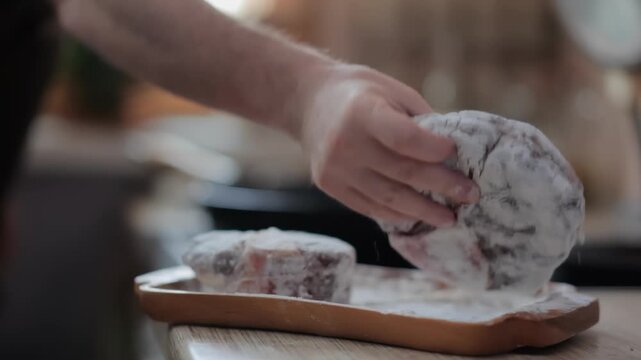 A man's hands transfer a raw Osso Buco steak from a plate to a hot skillet. The first step of searing the meat for a classic Italian recipe