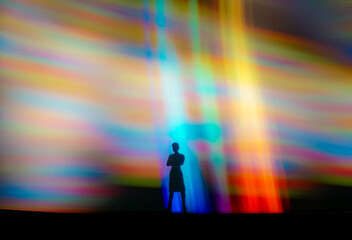Silhouette person standing in vibrant abstract light beams