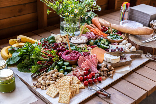 Vibrant catering spread on a wooden table at a campsite near Lake Yamanaka. Healthy grazing board with fresh fruits, vegetables, dips, and cheeses for a glamping event.