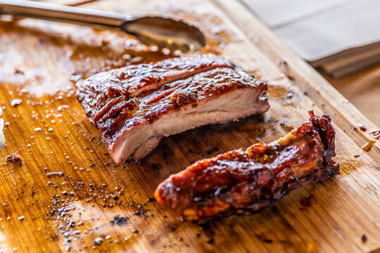 Close-up of slicing a grilled pork rib roast on a wooden cutting board. Juicy roasted pork being carved at an outdoor barbecue.